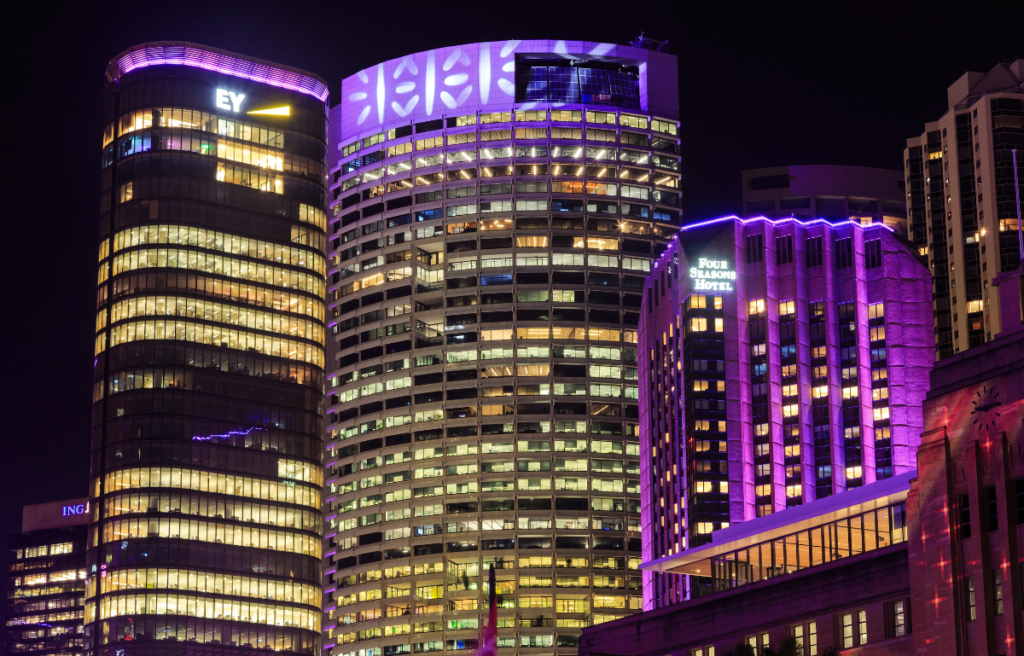 Skyscrapers of central Sydney, Australia, illuminated at night with colorful lighting. To the right is the Four Seasons Hotel in Sydney, Australia: By Ali Reza.
